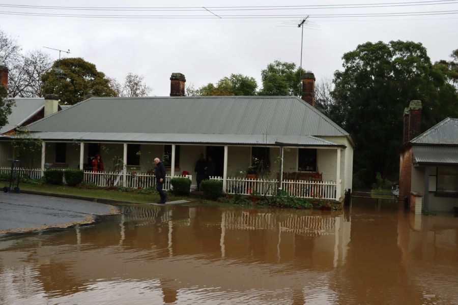 Man standing outside of a flooded house.