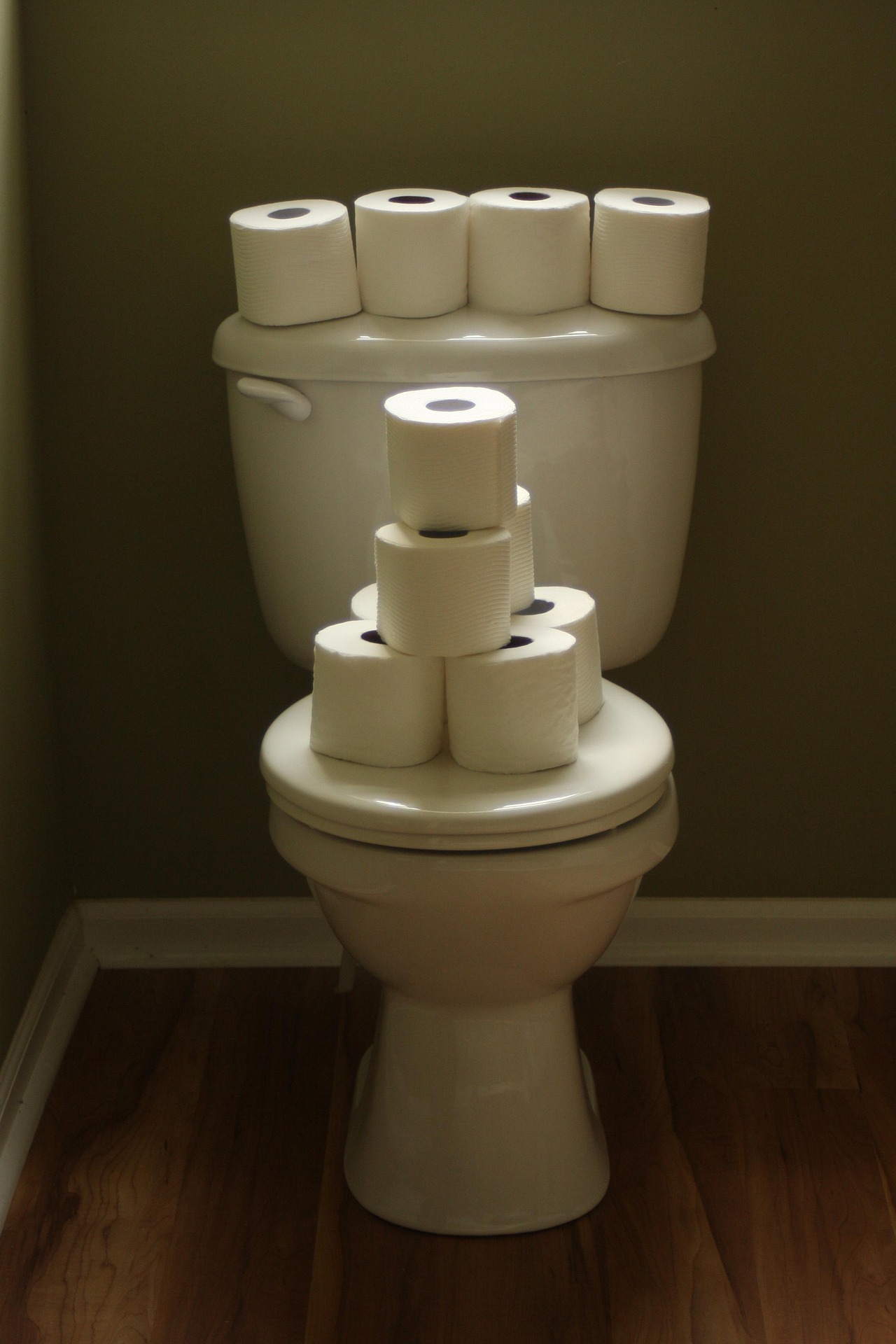 A toilet with rolls of toilet paper stacked on it.